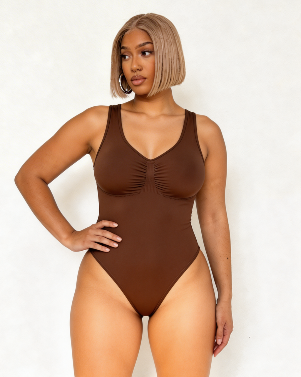 Woman wearing a brown one-piece swimsuit against a white background